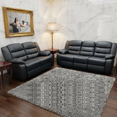 Black leather sofa set in a living room with marble walls and a gray rug.