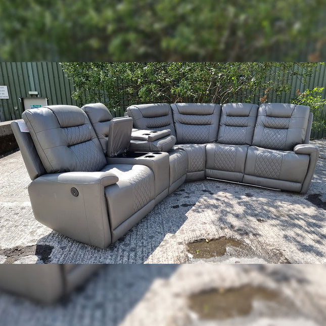 Gray sectional sofa outdoors on a gravel surface with greenery in the background
